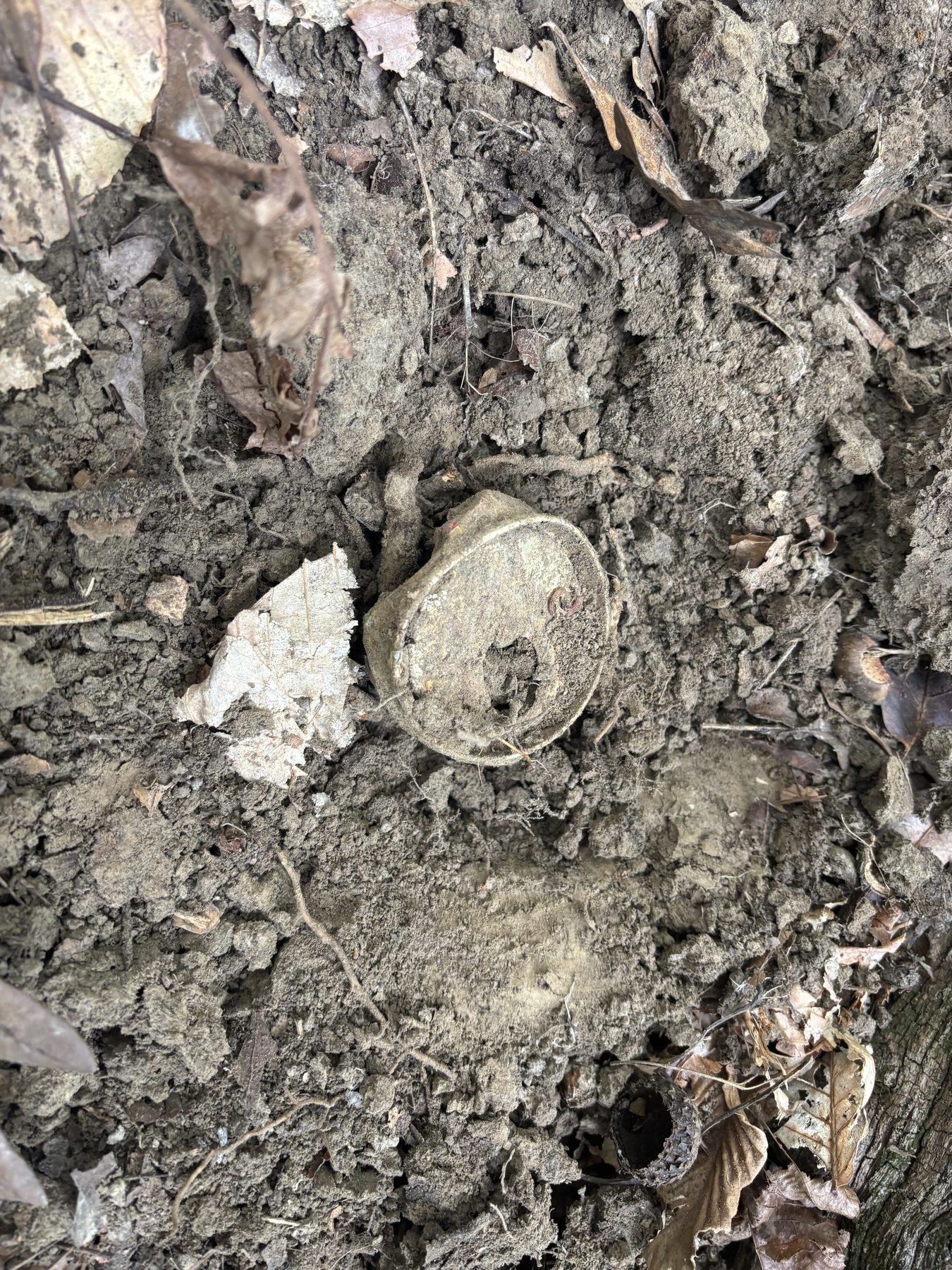 Another corroded can partially buried in dirt